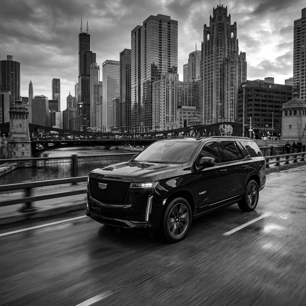 Black Cadillac Escalade crossing a Chicago River bridge downtown